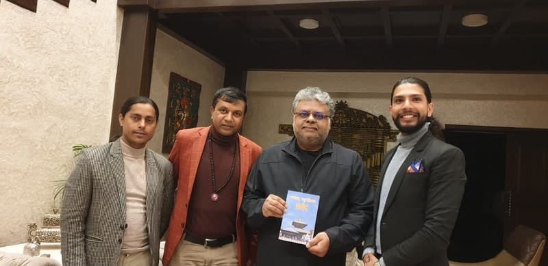 Samir with three men, one holding a book